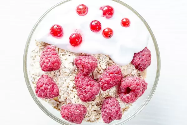 Tasty oatmeal porridge with raspberries and red currant, close up view