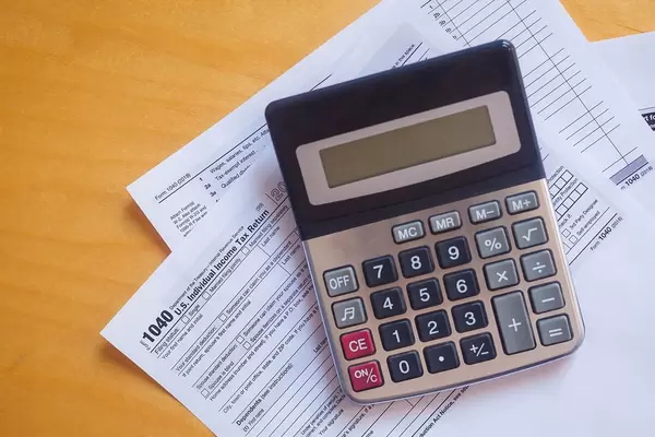 Tax form 1040 and a calculator. US tax form law document on a wooden desk. Business concept