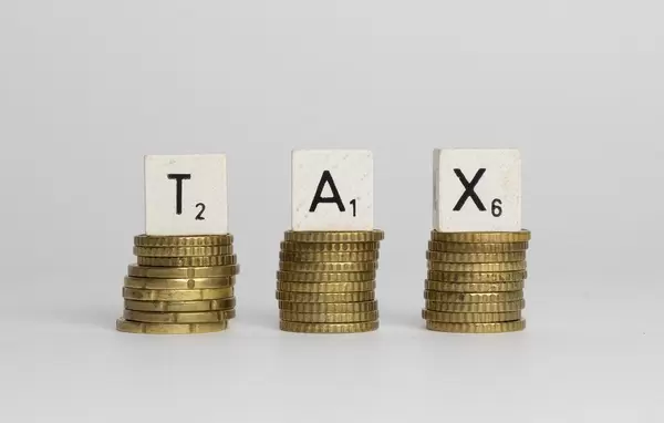 TAX in Würfel-Schrift auf Stapel Münzen