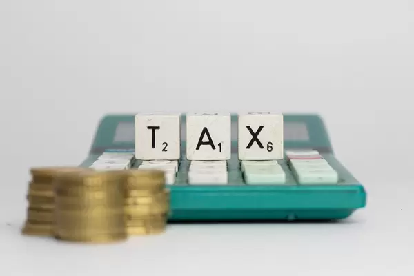 TAX - Steuern Schrift mit Münzen auf einem Taschenrechner