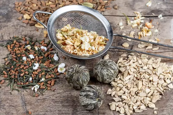 Tea background with different varieties of teas and a sieve on a wooden background