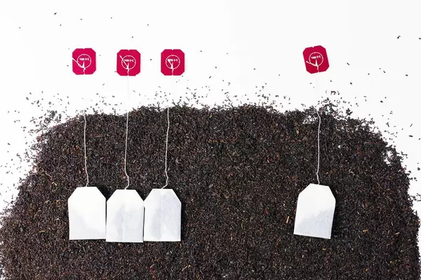 Tea bags over dry tea, white background