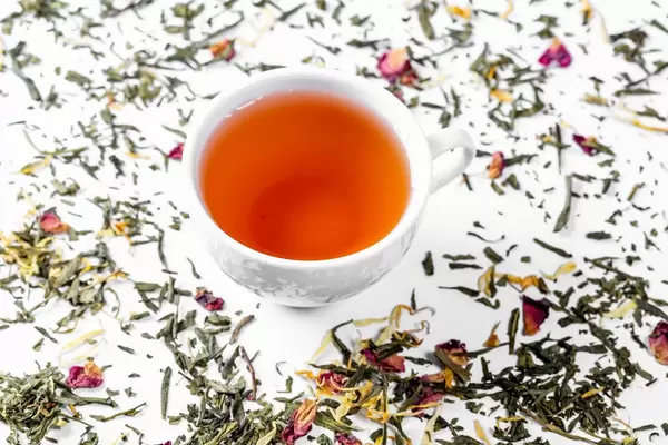 Tea cup with tea leaves on white. Tea time