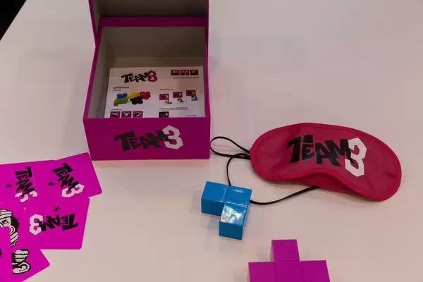 Team 3 Spiel ausgebreitet auf einem weißen Tisch mit Spielmaterial und Rollenkarten