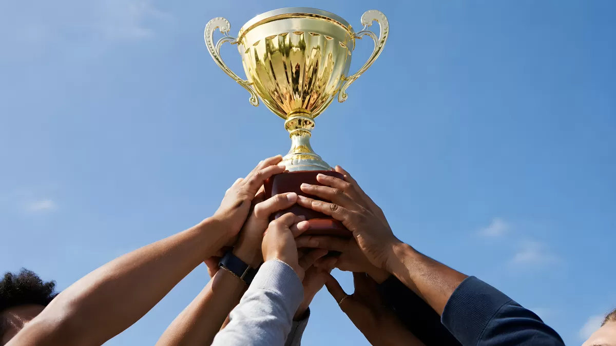 Team hält gemeinsam goldene Siegertrophäe in den Himmel