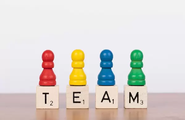 Team-Konzept mit bunten Spielfiguren und Scrabblesteinen