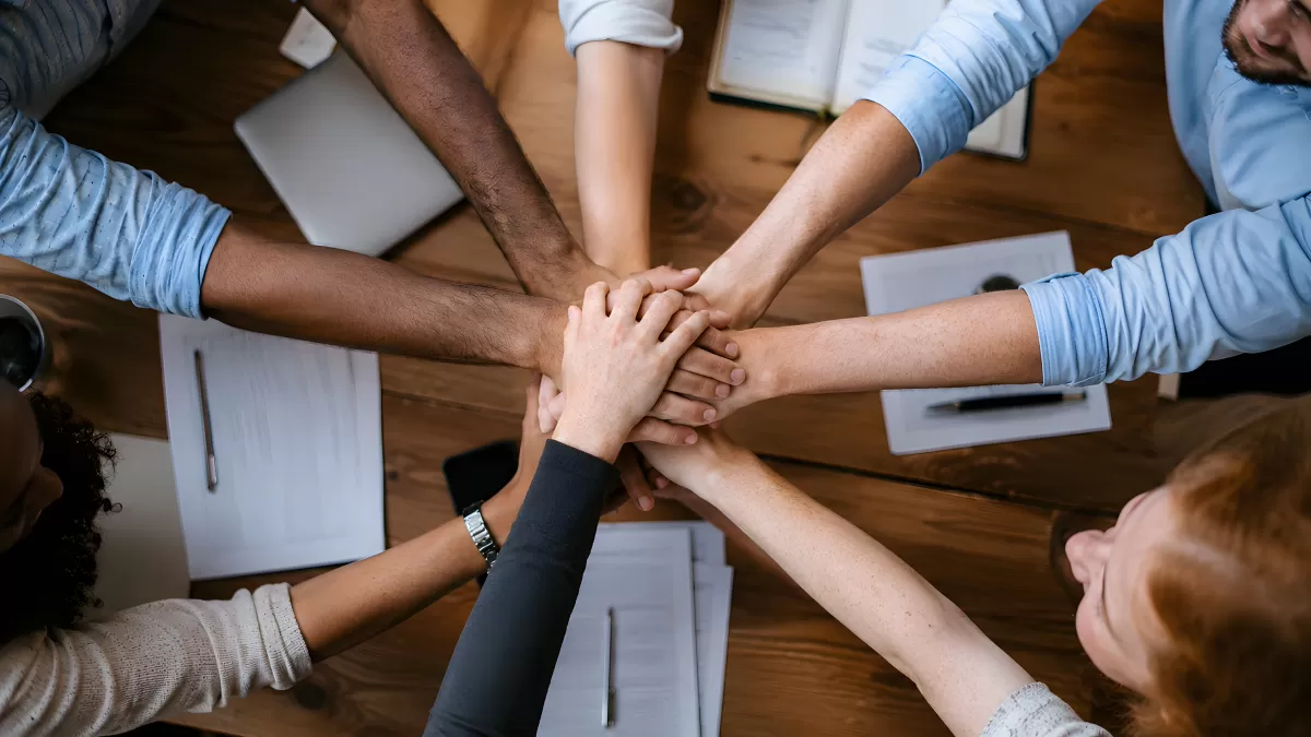Teamwork: Hände stapeln sich über Konferenztisch