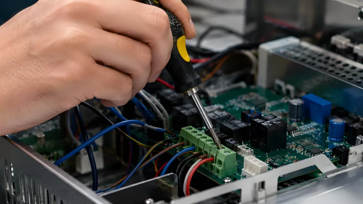 Techniker justiert Platine mit Schraubenzieher im Gerät