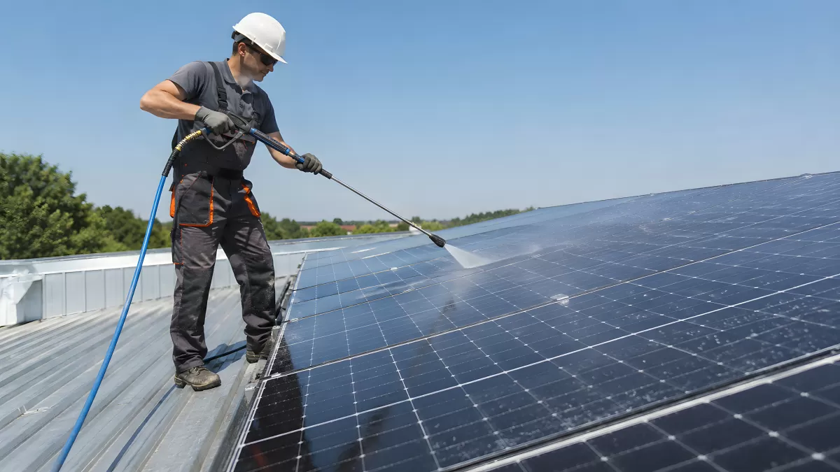 Techniker reinigt Solaranlage auf Hausdach mit Hochdruckreiniger