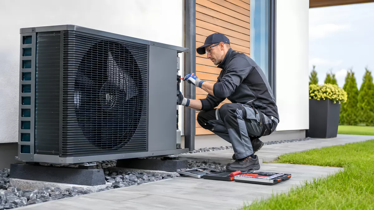Techniker wartet Wärmepumpe an Hausfassade
