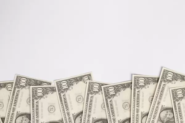 Teilweise sichtbare US-Dollar Geldscheine vor weißem Hintergrund