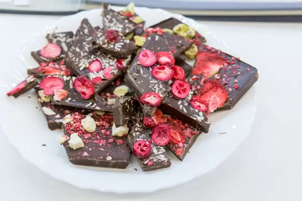 Teller mit Schokoladenstücken, rotem Früchte-mix und Kokosraspel