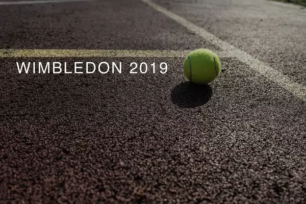 Tennis ball located on a tennis court next to the name of the London sports event "Wimbledon 2019"