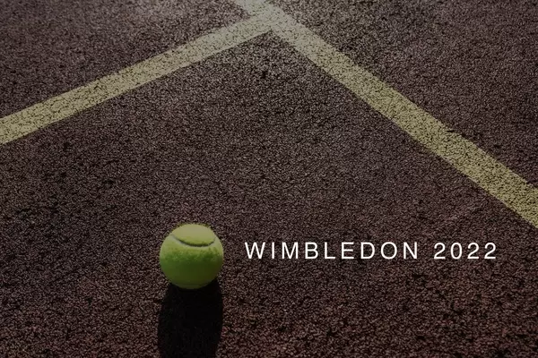 Tennisball liegt auf der Spielfläche eines Tennisplatz neben dem Namen des Londoner Sportevents "Wimbledon 2022"