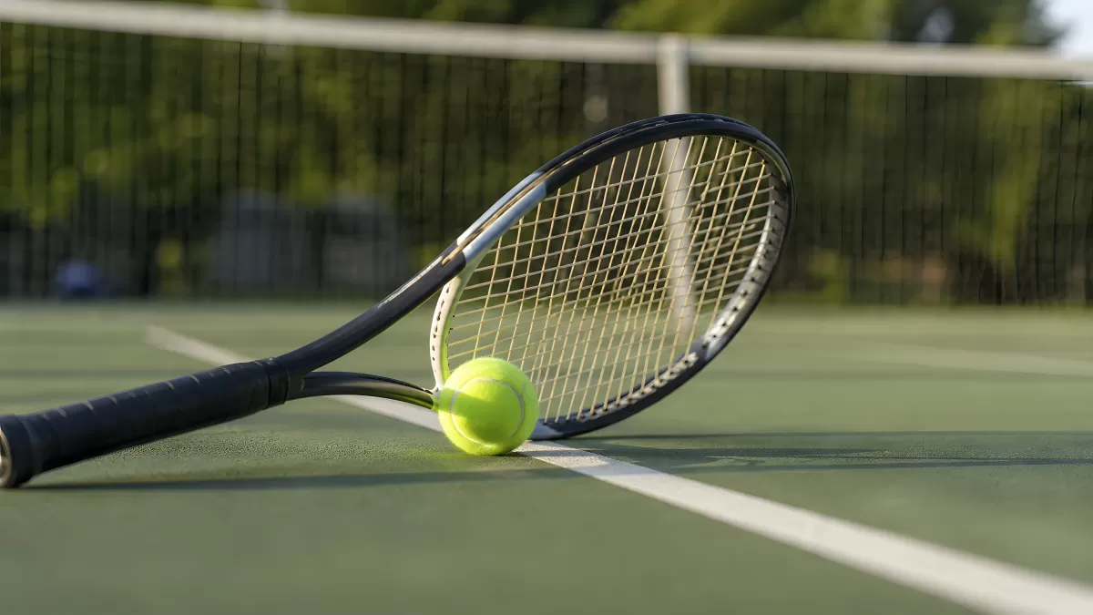 Tennisschläger und Tennisball auf grünem Hartplatz