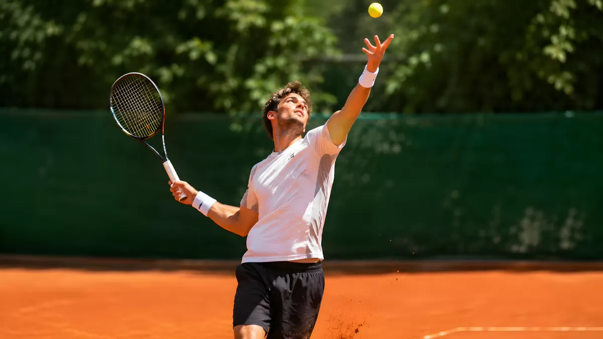 Tennisspieler serviert auf rotem Sandplatz