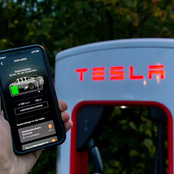 Tesla Aufladen mit der Supercharging Funktionalität in der App vor einer Tesla Ladesäule