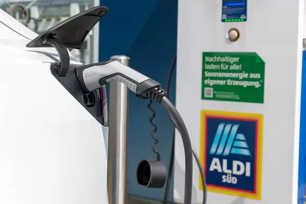 Tesla E-Auto an der Ladestation mit dem Ladestecker Typ 2, auf einem Parkplatz von Aldi Süd, tankt Sonnenenergie aus eigener Erzeugnis