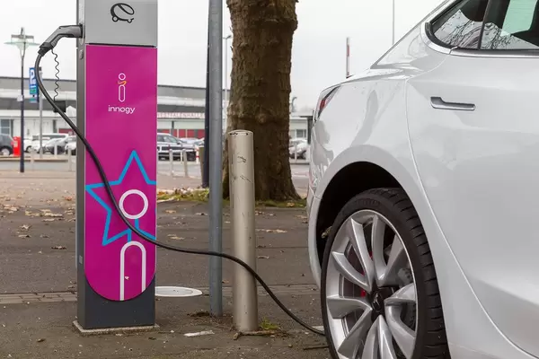 Tesla-Elektrofahrzeug Model 3 während der Aufladung mit Phoenix Contact Stecker an der innogy Ladestation