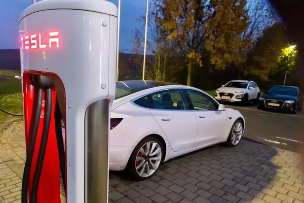 Tesla Super Charger Ladestation mit beleuchtetem Schriftzug bei Dunkelheit