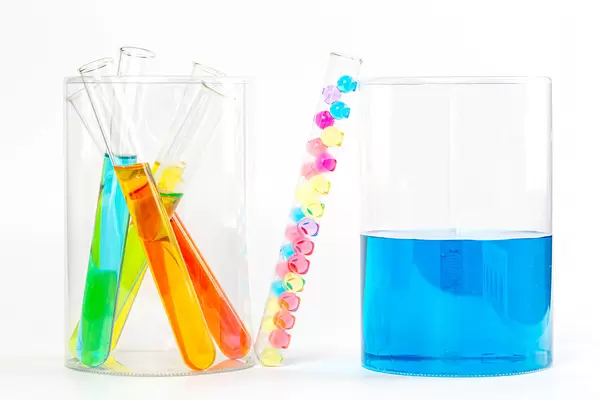 Test tubes in laboratory with colorful liquids and balls on white