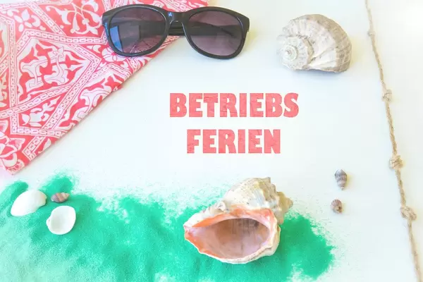 Text Betriebsferien zwischen Muscheln und Sonnenbrille auf weißem Hintergrund