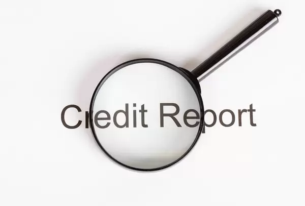 Text Credit Report unter einer Lupe mit weißem Hintergrund