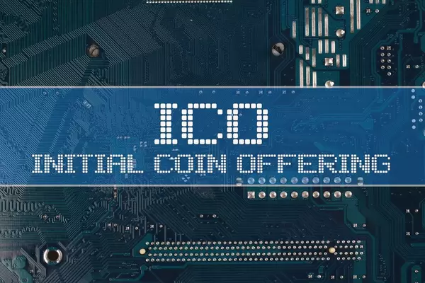 Text ICO Initial Coin Offering zu Deutsch Erstes Münzangebot vor einer elektronischen Leiterplatte als Hintergrund