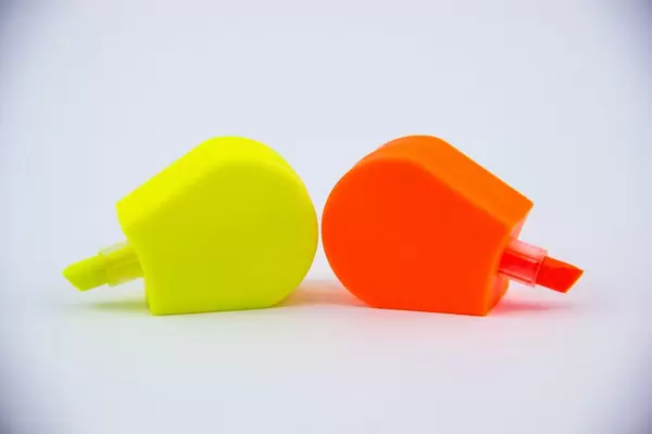 Textmarker in gelb und orange in der Form von Eis am Stiel auf weißem Hintergrund