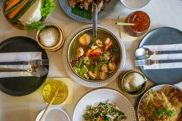 Thailändische Gerichte wie Tom Yum Suppe, Papaya Salat, Pad Kra Pao und Sticky Reis in einem Thai Restaurant Draufsicht