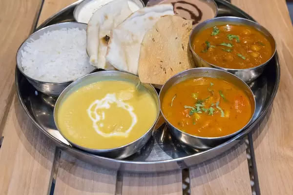 Thali Lunch - Chicken Korma - Hünchenbrust in cremigem Kokosnuss-Cashew-Curry, mit Basmati Reis, Fladenbrot, Aloo Tamatar, Chole Masala, Raita und Schokoladencreme als desert