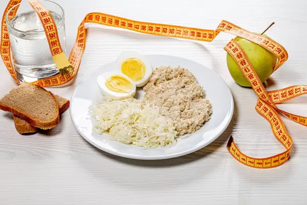 The concept of a healthy diet. Low calorie lunch with measuring tape on white wooden background (Flip 2019)