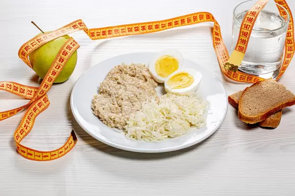 The concept of a healthy diet. Low calorie lunch with measuring tape on white wooden background