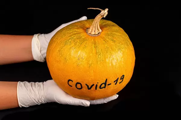 The concept of autumn holidays under quarantine restrictions. Pumpkin in hands on black