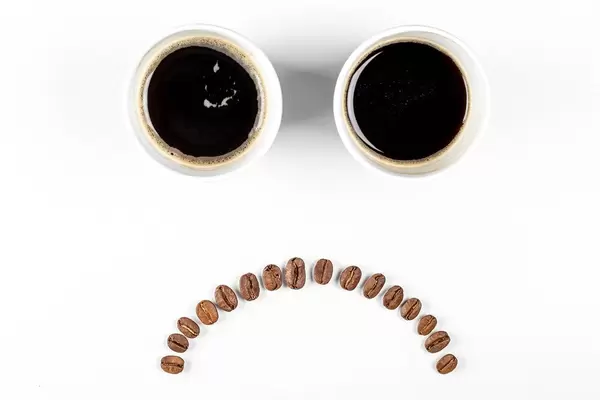The concept of bad mood, failure. Sad emoticon of coffee and coffee beans