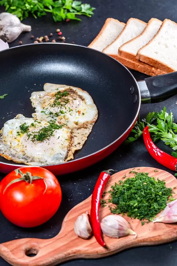 The concept of cooking Breakfast-fried chicken eggs in a frying pan with slices of bread, herbs and vegetables (Flip 2019)
