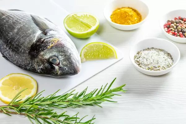 The concept of cooking fish. Raw Dorada and spices on white wooden background (Flip 2019)