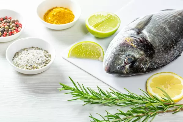 The concept of cooking fish. Raw Dorada and spices on white wooden background