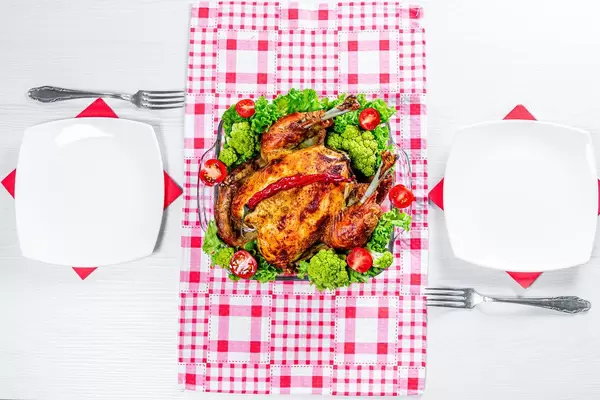 The concept of dinner for two. Baked chicken with vegetables and Cutlery on the table (Flip 2019)