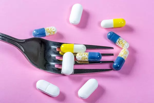 The concept of drug nutrition-encapsulated medicines with a fork on a pink background