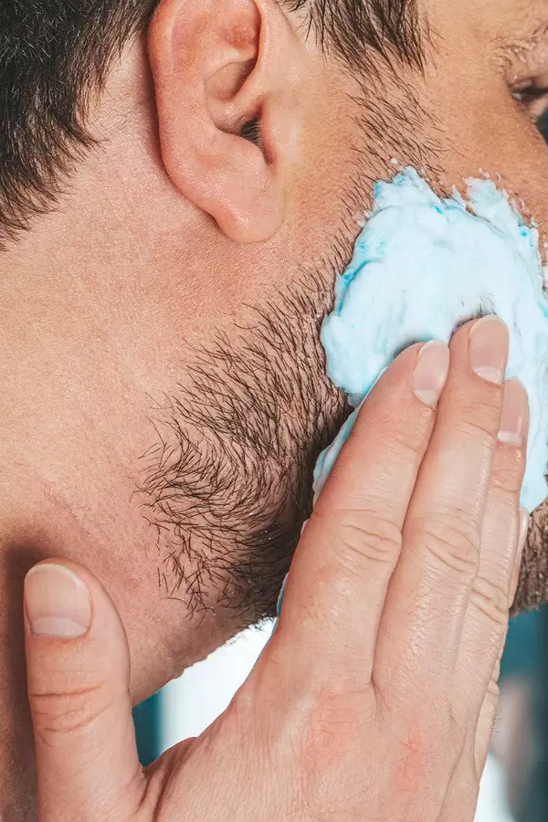 The concept of facial care for men. A man applies shaving gel to his face (Flip 2019)