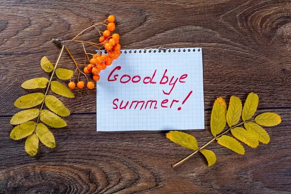 The concept of goodbye summer. Autumn yellow leaves with Rowan and note on wooden background