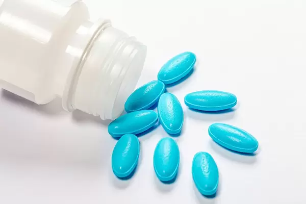 The concept of medication treatment. Blue pills on white background with plastic open packaging (Flip 2019)