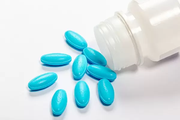 The concept of medication treatment. Blue pills on white background with plastic open packaging