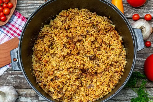 The concept of oriental cuisine. Homemade pilaf served in cast iron cookware