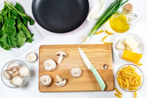 The concept of starting cooking. Mushrooms, herbs, pasta and other ingredients of the dish. Top view