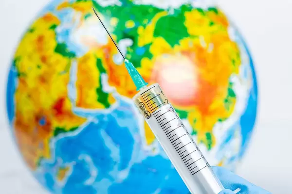 The concept of vaccination. Syringe on the background of the globe