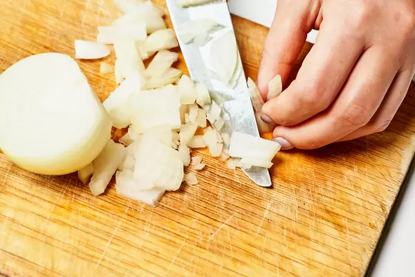 The cook cuts the onion on a cutting board
