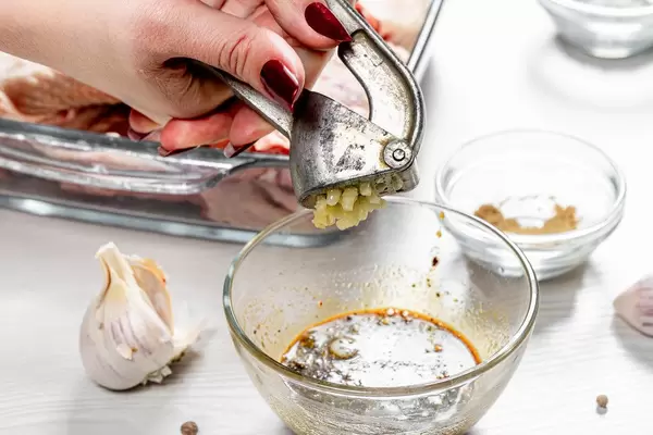 The cook squeezes the garlic with a garlic grinder into the marinade sauce (Flip 2019)