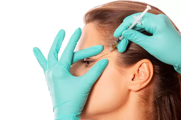 The doctor cosmetologist makes injection procedure for tightening and smoothing wrinkles on the face skin of a beautiful woman